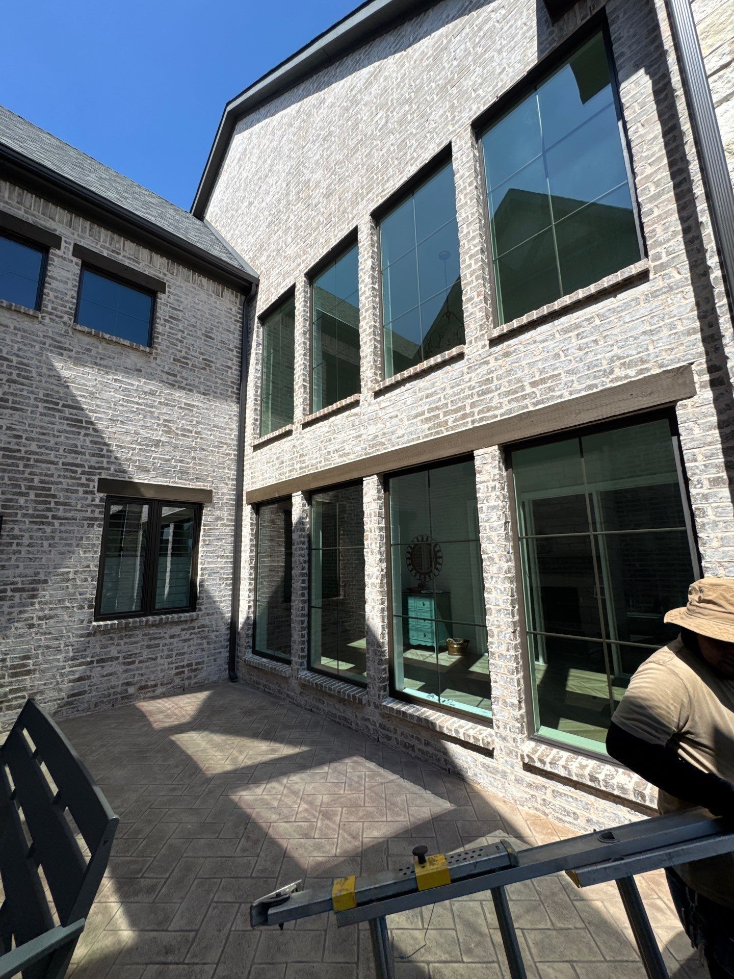 Large black-framed windows being installed on a brick home