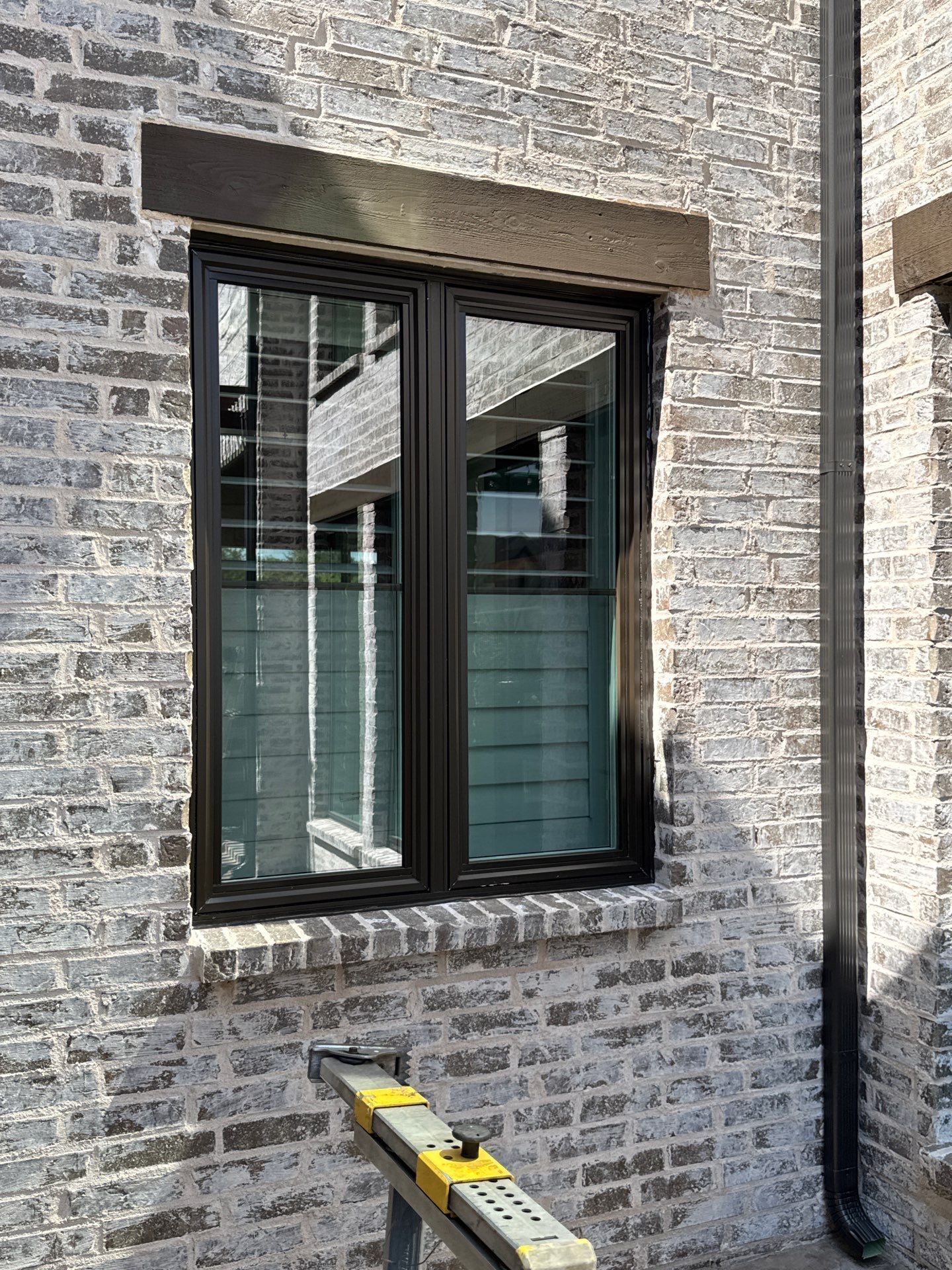 Black-framed window on brick, install in progress